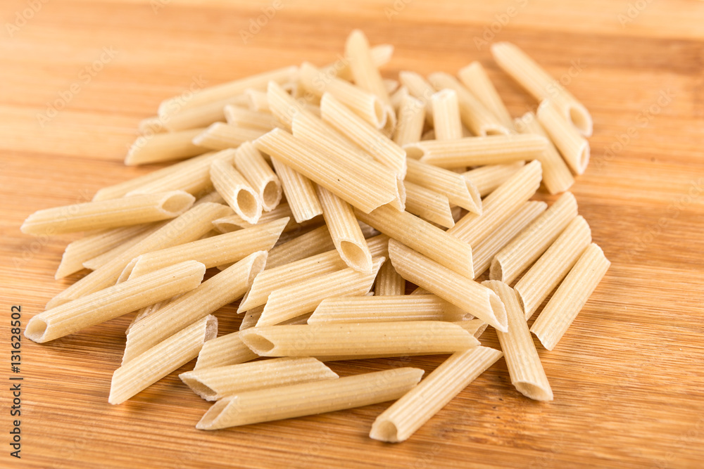 Brown rice penne isolated on a wood background Brown rice penne isolated on a wood background
