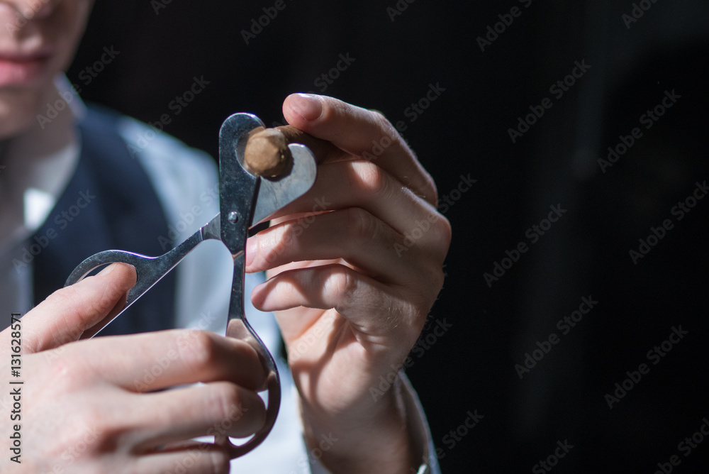 Fototapeta premium man cuts a cigar