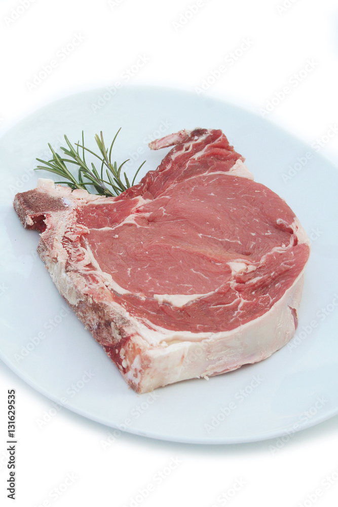 Bistecca di manzo con l'osso su piatto con rosmarino isolato su sfondo bianco Bistecca di manzo con l'osso su piatto con rosmarino isolato su sfondo bianco