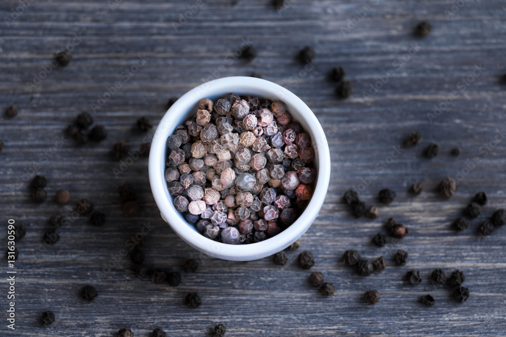 Black pepper in bowl and on wooden table. Selective focus, speci Black pepper in bowl and on wooden table. Selective focus, speci