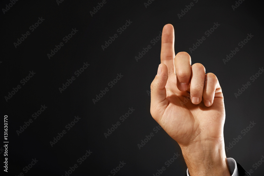 Male hand with finger pointing on dark background Male hand with finger pointing on dark background