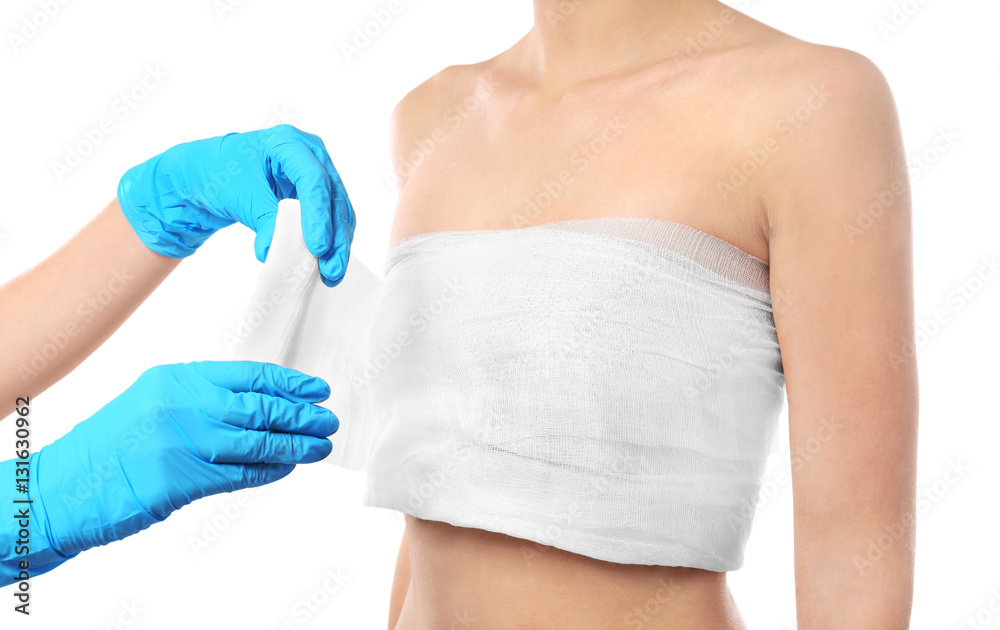 Foto de Doctor wrapping bandage around young woman's chest on white  background, closeup do Stock