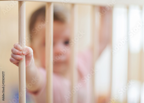 Sad baby stay alone in crib frame