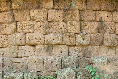 stone block wall - a wall made of yellowish rectangle and square porous volcano stone cubes, located in the ancient overgrown ruins of Angkor photo