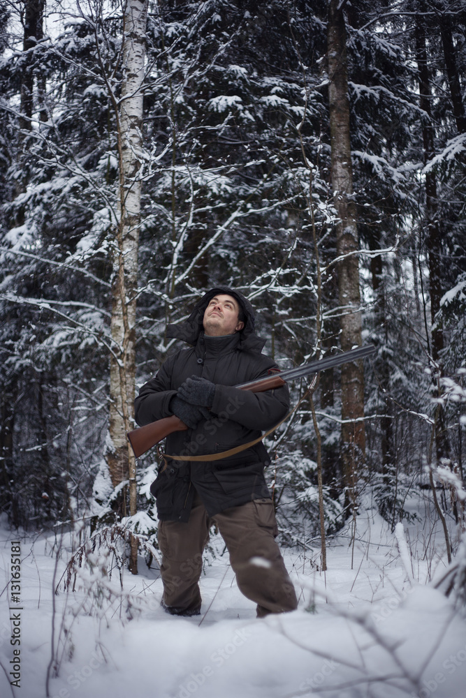 Hunter with a gun. Hunting in the winter forest.