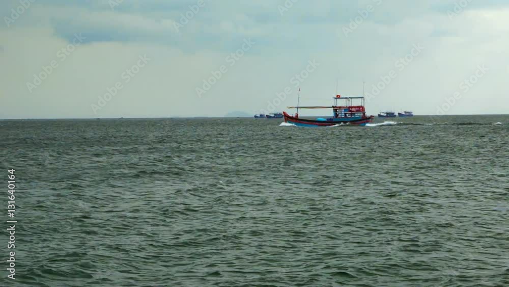 Fishing motor boats floating on the sea. In the background, a large green mountains covered with forests. Fishing motor boats floating on the sea. In the background, a large green mountains covered with forests.