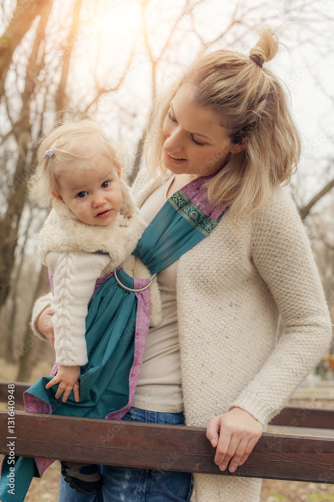 Young mother having her little daughter in baby carrier scarf Young mother having her little daughter in baby carrier scarf