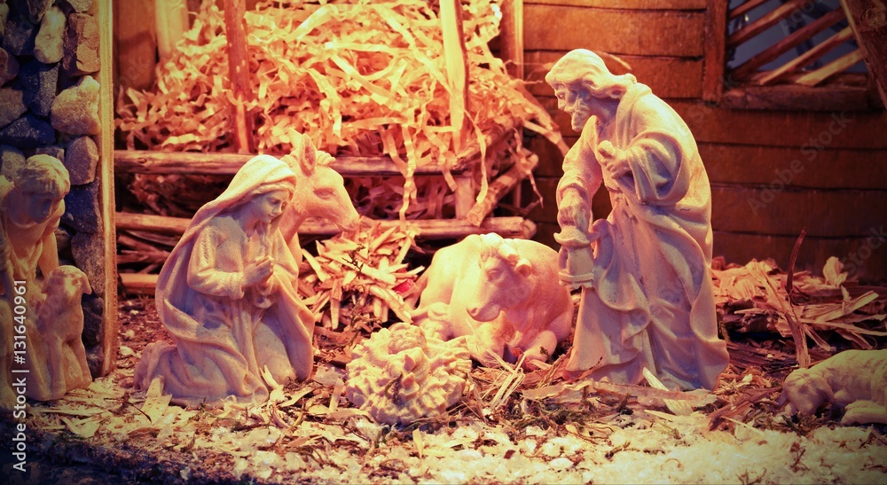 Nativity scene with wooden statues and the manger with straw and