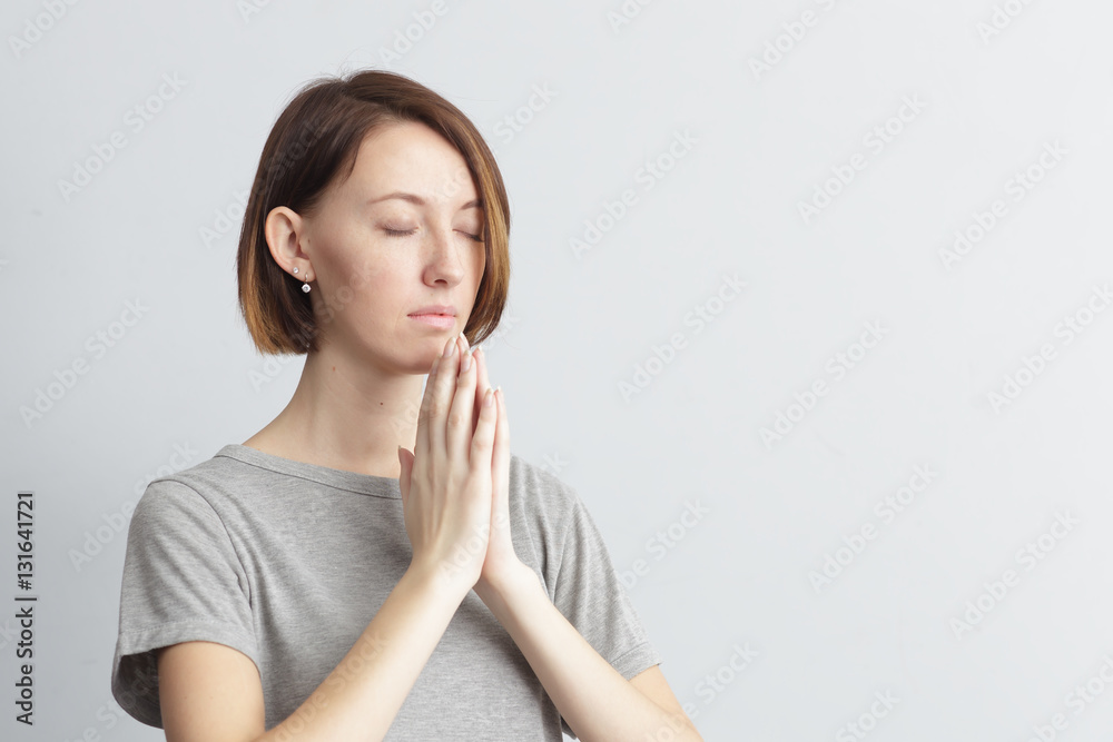 Girl holding hands together, elbows to the sides. Eyes closed. Girl holding hands together, elbows to the sides. Eyes closed.