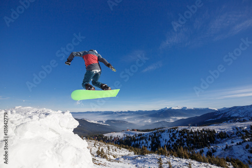 Jumping snowboarder in mountains in ski resort on blue sky background Dragobrat