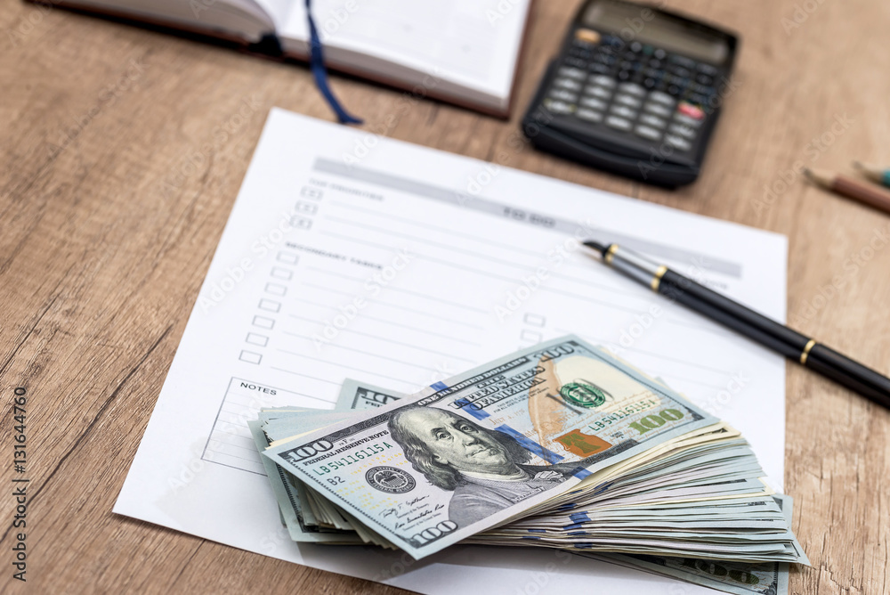 dollars and calculator with blank sheet on the table dollars and calculator with blank sheet on the table