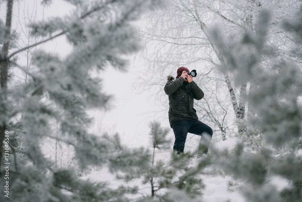 Traveler photographer taking pictures in the winter forest