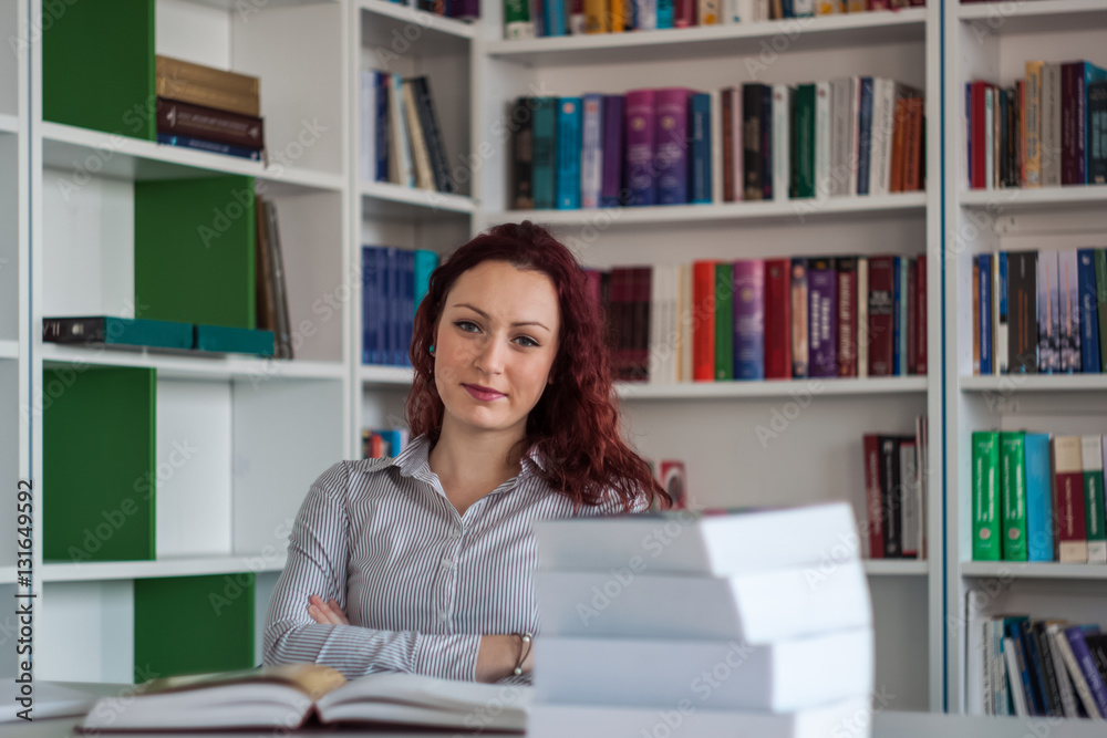 Beautiful redhead girl sitting and thinking with books around wi Beautiful redhead girl sitting and thinking with books around wi