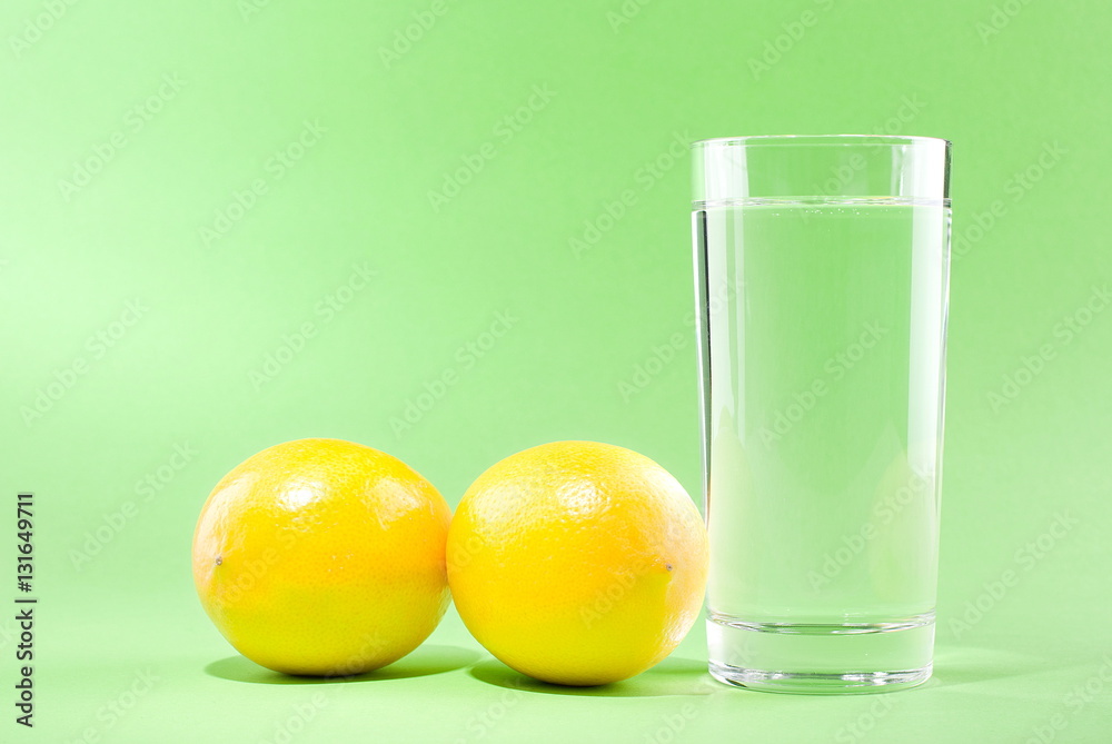 glass of water with lemon on a green background