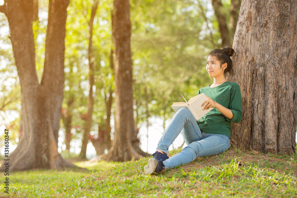 Beautiful young asian woman sitting and reading book in a park Beautiful young asian woman sitting and reading book in a park