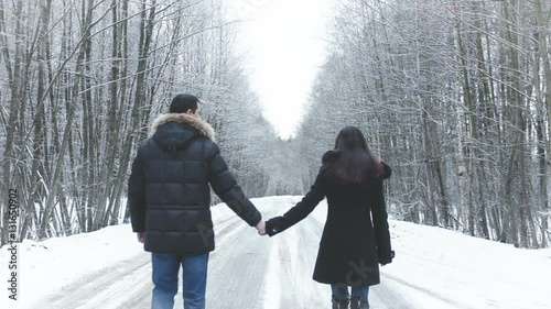Girl and boy walking along the road into the woods. hold hands