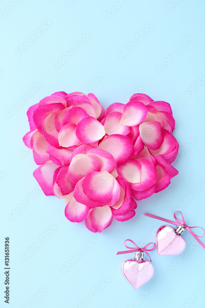 Heart shape of pink rose petals with pink hearts on pastel blue background