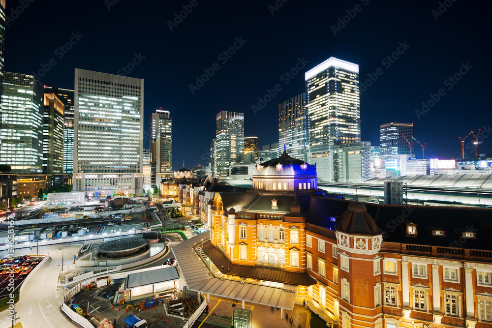 Asia Business concept for real estate and corporate construction - panoramic modern cityscape building bird eye aerial night view of Tokyo Station under neon light and dark blue sky in Tokyo, Japan