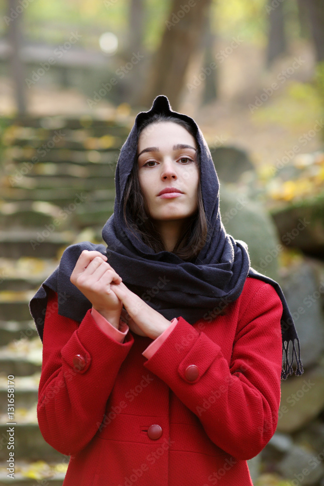 Girl in black scarf walks in autumn park.