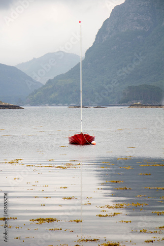 Single red Sail Boat moored on Loch Carron, Scotland on bleak day 