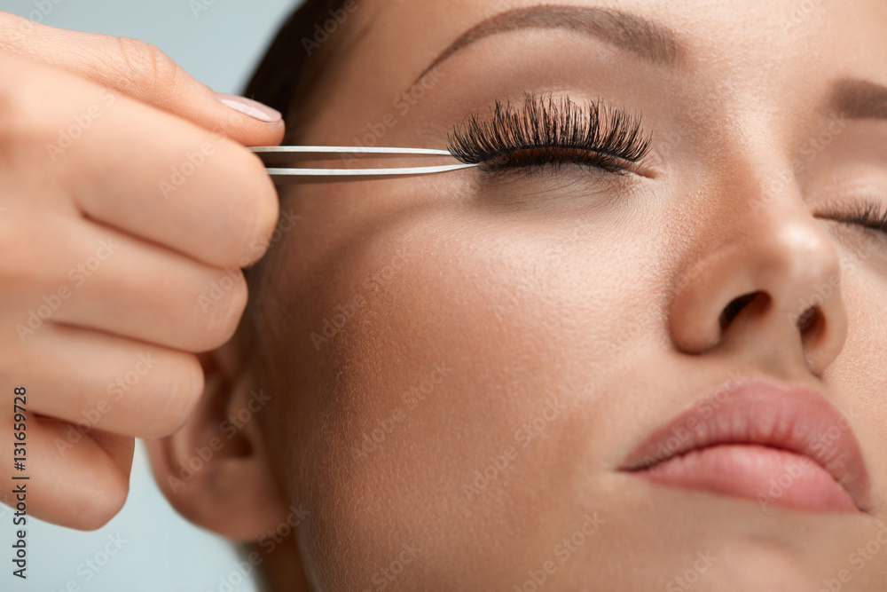 Beauty Makeup. Woman Applying Black False Eyelashes With Tweezer