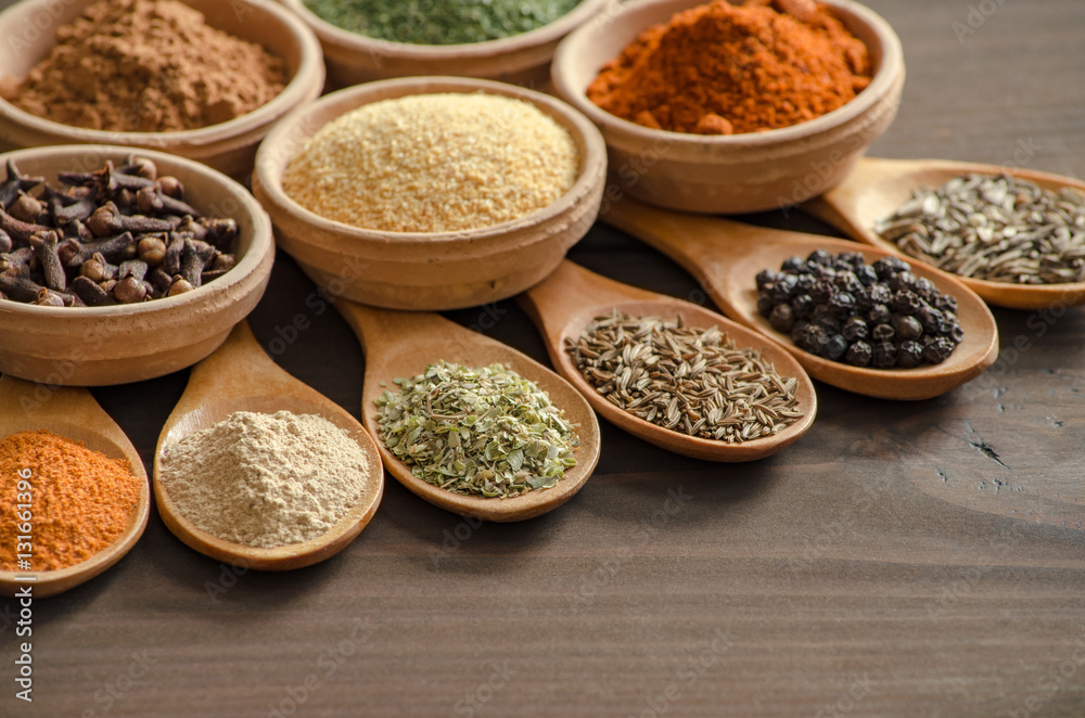 Colorful spices and dried herbs on wooden spoons