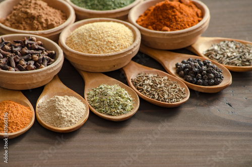 Colorful spices and dried herbs on wooden spoons