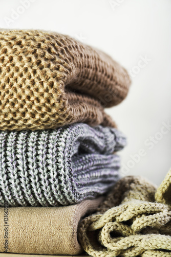 warm sweaters are stacked on the table on a light background ver