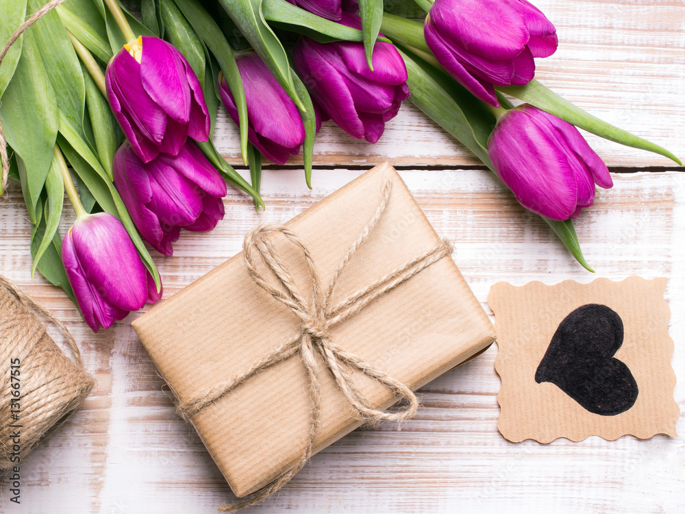 Gift box and tulips bouquet on white wooden background - retro style