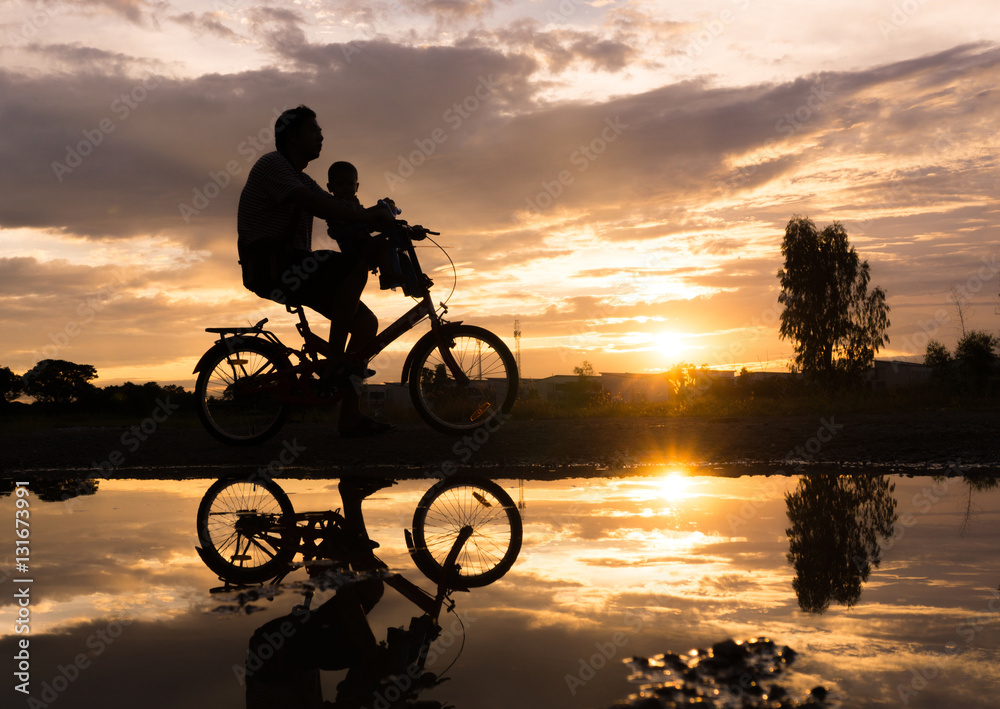 Fototapeta premium Reflection Silhouette of Father with his toddler on bicycle agai