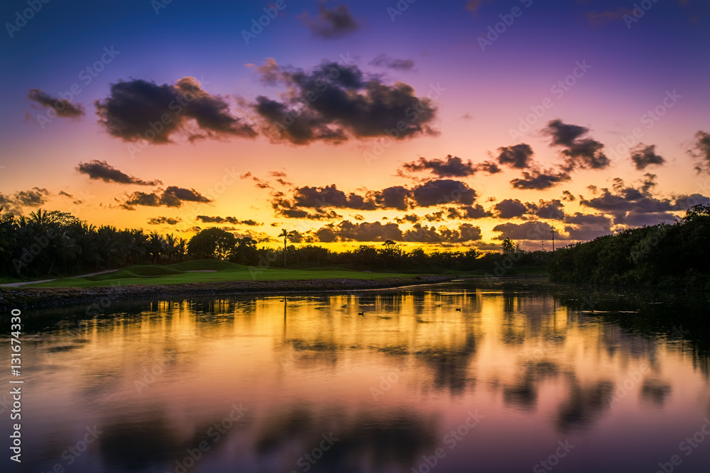 Beautiful sunset over the lake near the golf course in a tropica