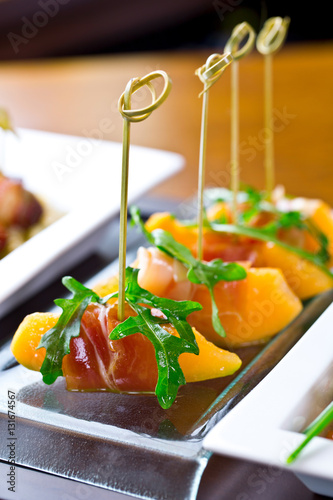 set of finger food, catering appetizers - prosciutto, melon, rucola photo