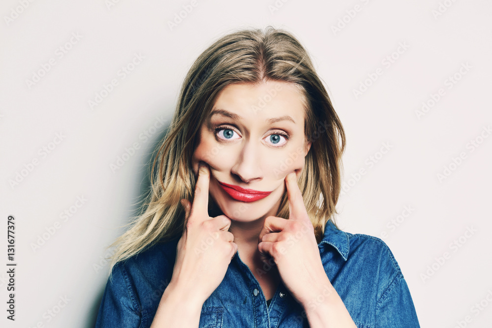 femme drôle blonde faisant un sourire forcé avec une grimace femme drôle blonde faisant un sourire forcé avec une grimace