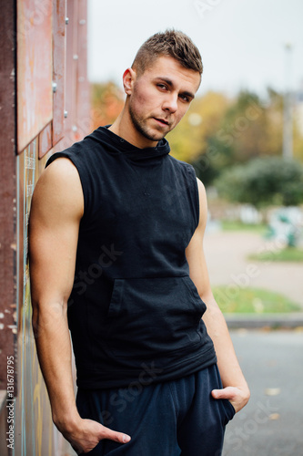 Portrait of a strong handsome man in training cloth. Posing in the hood. © photominus21