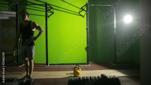 Young athletic man doing kettlebell swing exercise at the gym. CrossFit photo