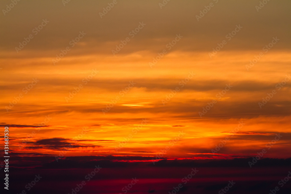 Sunset in clouds over red sunset sky background.