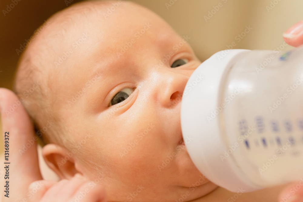 Cute newborn baby drinking milk from a bottle. Stock photo