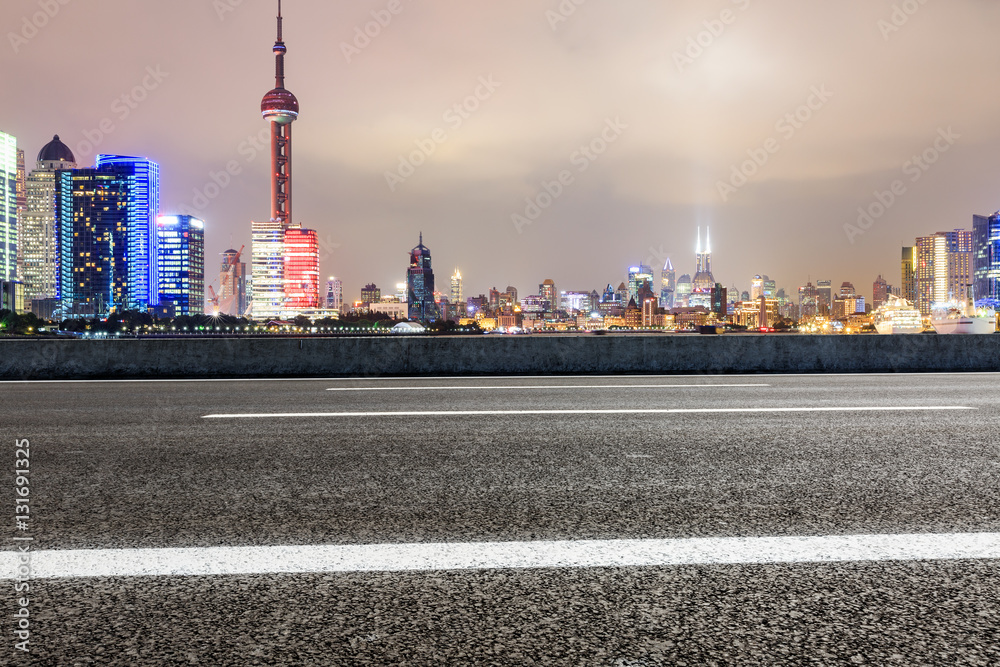 Asphalt road and modern cityscape at night in Shanghai