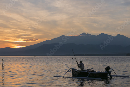 Sunset with fisher man fishing in a boat in ocean near Gili Air