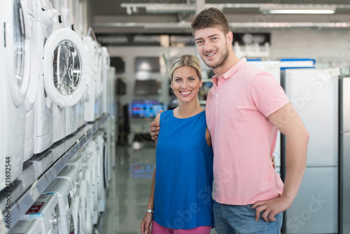 Beautiful Young Couple Shopping Washing Machine In Supermarket