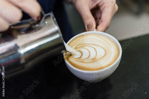 Hands of barista pouring milk to form a latte art photo
