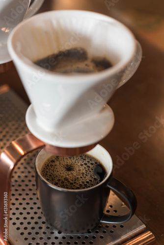Hand of barista dripping coffee with white dripper filered by paper