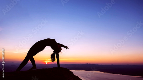 Fototapeta Naklejka Na Ścianę i Meble -  Silhouette woman with yoga posture on the mountain at sunset.
