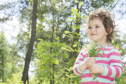Spring in the forest little girl holding a small bouquet lily of