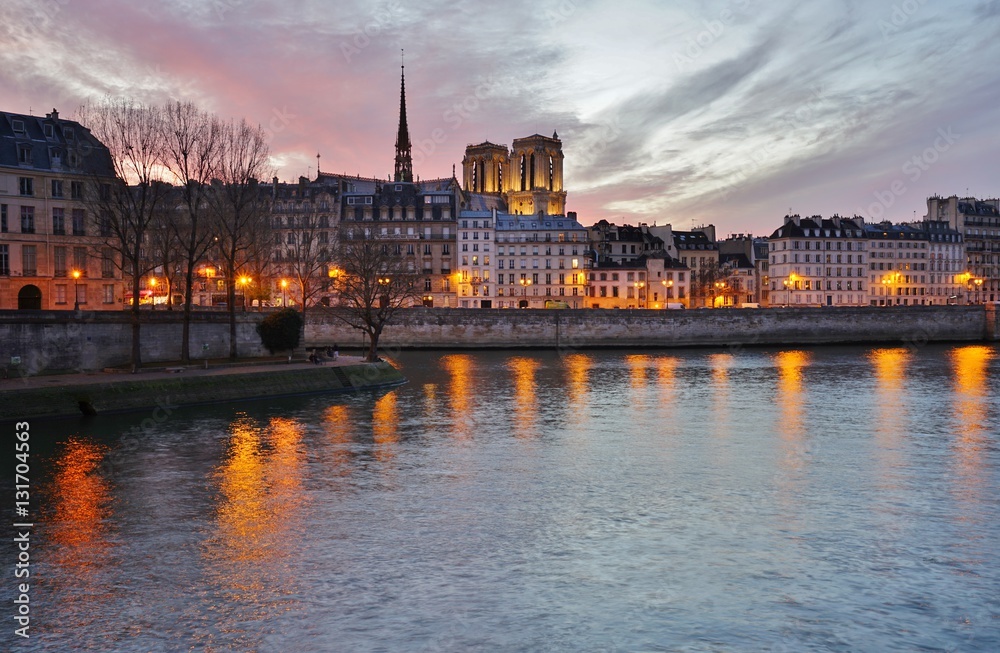 Beautiful pink sky at sunset over the Notre-Dame cathedral and the Seine River in Paris, France