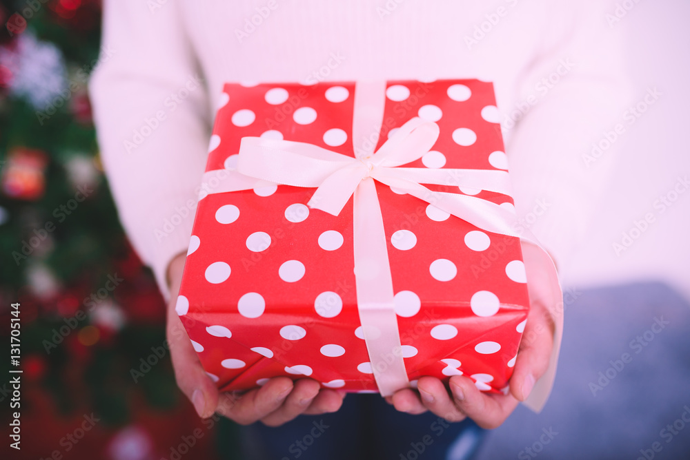 Female hands holding a red christmas gift box.