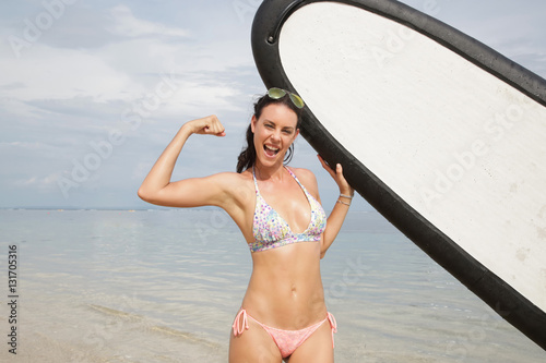 Young attractive woman holding a surf board