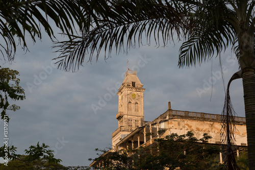 Beit-al-Ajaib (House of wonders) in Zanzibar Stone town. Lit up with sunlight and framed with foliage.