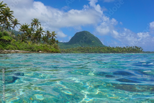 Coastal landscape of Huahine island, islet with coconut trees and the mount Moua Tapu seen from the lagoon, south Pacific ocean, French Polynesia
