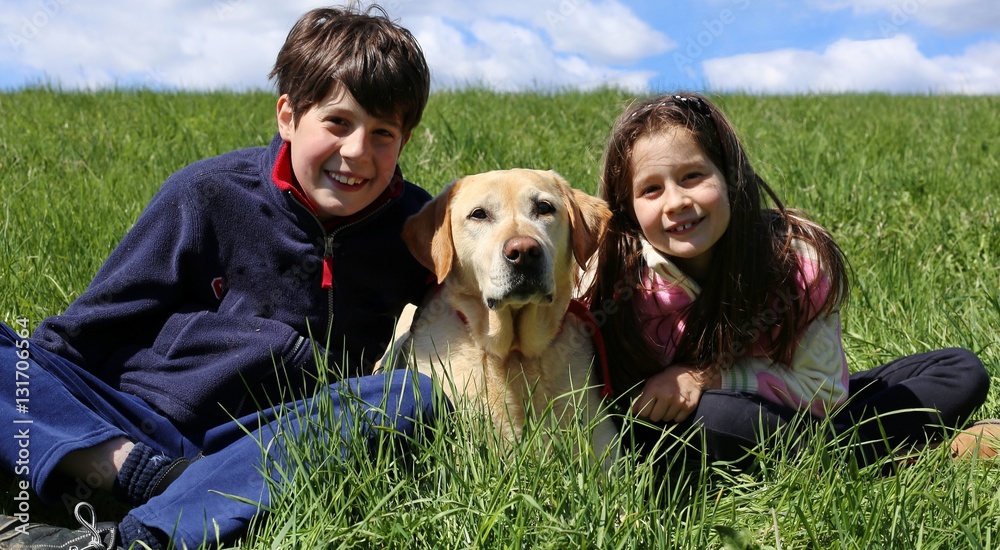 young brother and little sister smiling with their labrador dog young brother and little sister smiling with their labrador dog